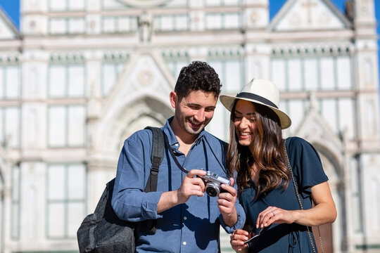 Smiling tourists checking camera with Basilica Of Santa Croce in background at Florence, Italy