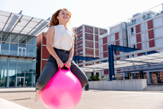 Female freelancer smiling while jumping with bouncy ball
