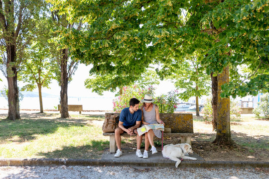 Tourist couple checking map while sitting on bench