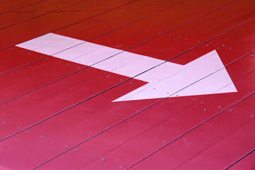 white arrow on red wooden floor