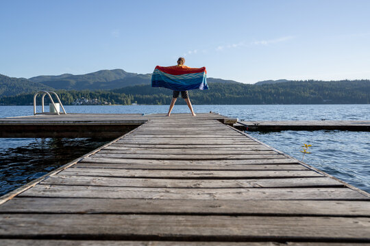 Boy in a towel stands at end of dock