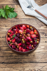 Vinaigrette with beetroot and boiled vegetables, traditional Russian homemade salad. Wooden rustic background, copy space.