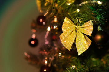 Artificial Christmas tree with gold decoration. Blurry, colorful background. 