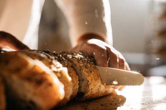 Crop baker cutting a slice of bread