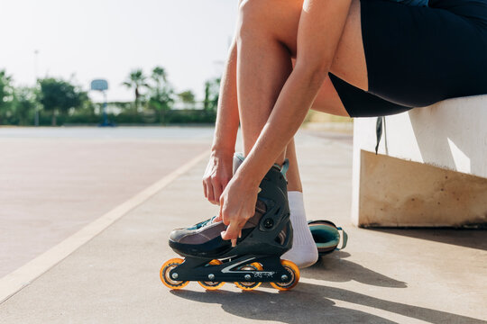Woman wearing inline skate at basketball court during sunny day