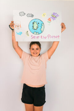 Smiling girl with arms raised holding poster at home