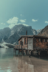 landscape of a wooden house in the middle of a river surrounded by mountains