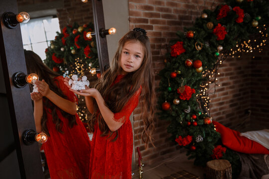 Cute little girl in red dress posing near mirror