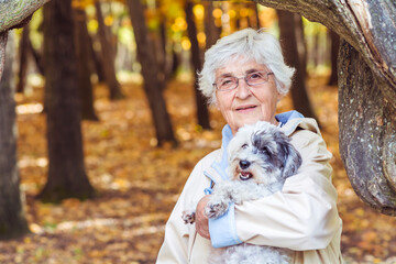 Beautiful Smiling Senior Woman Hugging her Havanese Dog in the Autumn Park
