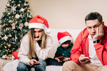 Portrait of depressed family with son playing cell phone during new year party. Tired mom and dad...