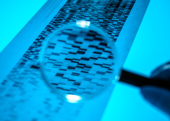Hand of scientist usingmagnifying glassto analyze DNA sequencing result chart