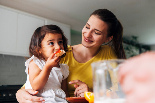 Daughter Eating Breakfast With Mother At Home