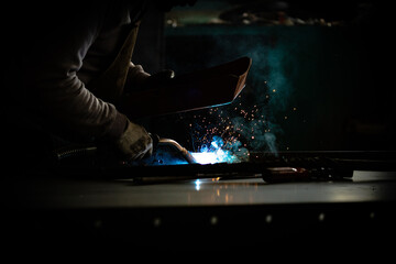 welder is welding in dark workshop