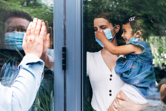 Man greeting family through glass door during COVID-19
