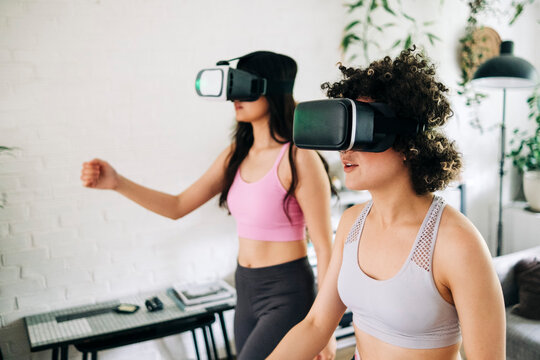 Friends with virtual reality headsets exercising together at home