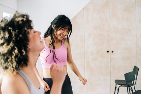 Female friends exercising together at home
