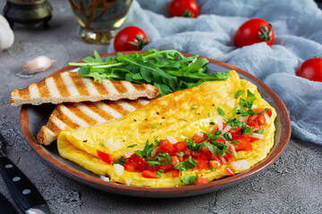 Fried omelette with tomatoes, onion and herbs. Delicious breakfast with eggs and toasts