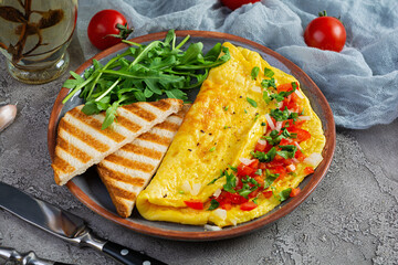 Fried omelette with tomatoes, onion and herbs. Delicious breakfast with eggs and toasts