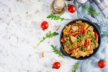 Tasty pasta in tomato sauce with chicken, pepper and herbs on white background. Top view