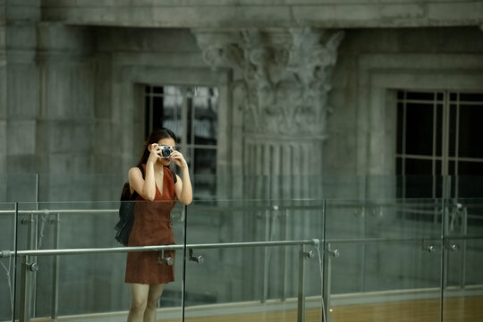 Female tourist photographing through camera while standing at glass railing