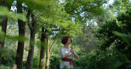 Female practicing qigong and meditation in summer park or forest	