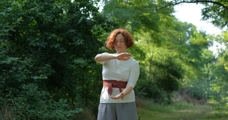 Female practicing qigong and meditation in summer park or forest	 - 473752067
