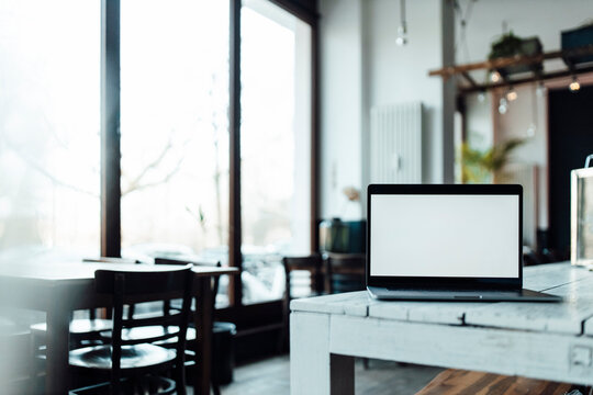 Laptop with blank screen on table in cafe