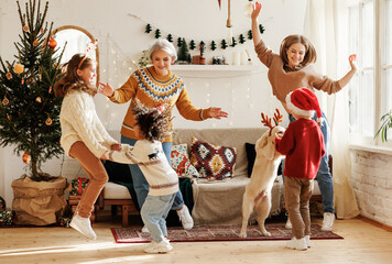 Happy multiracial family with three kids and golden retriever have fun on Christmas day at home