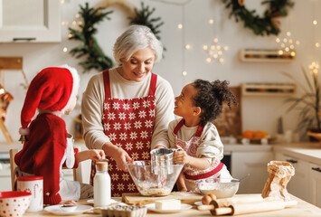 Happy multiracial kids help grandmother to cook Christmas cookies in kitchen during winter holidays