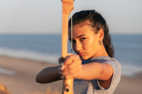 Serious woman practicing archery at beach