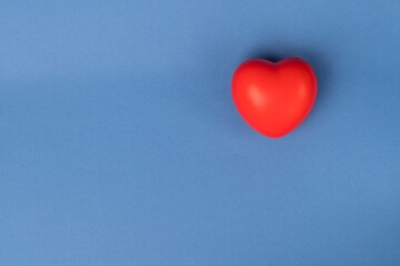 Rubber red heart on a blue background with space for text. 