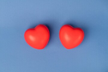 Two rubber red hearts on a blue background with space for text.