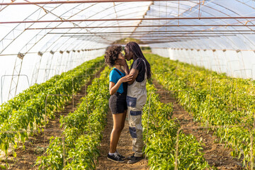 Affectionate mother kissing daughter on mouth while standing at greenhouse