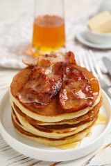 Delicious pancakes with maple syrup and fried bacon on white wooden table, closeup
