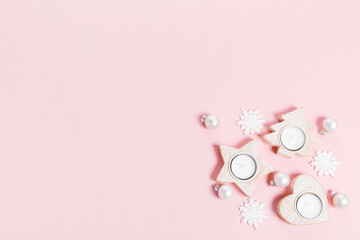 Christmas ornaments and decorations. white snowflakes and white candles on pink background. Minimal flat lay