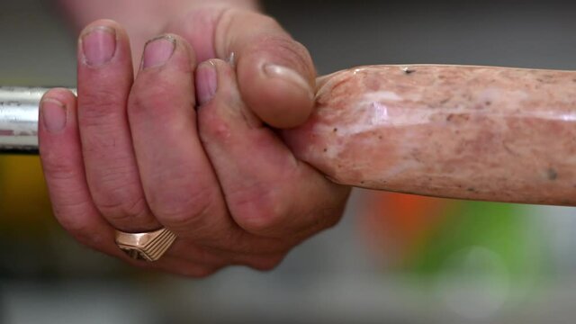 making sausages at home according to family recipes. salami product, meat industry, machine. shaping a stick of sausage into a natural casing