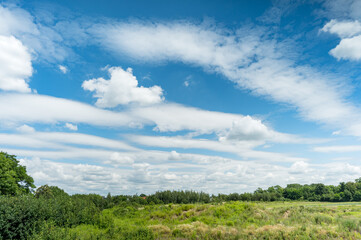 Fototapeta na wymiar White fluffy clouds in blue sky background in green countryside at summer