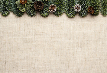 New Year's greeting. Linen background with fir branches and cones.