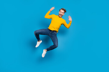 Full length body size of young guy jumping high overjoyed laughing careless playful isolated vivid...