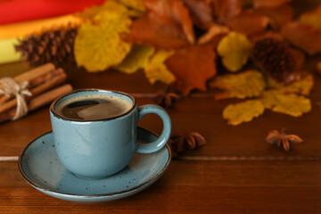 Composition with cup of hot coffee and autumn leaves on wooden table, space for text