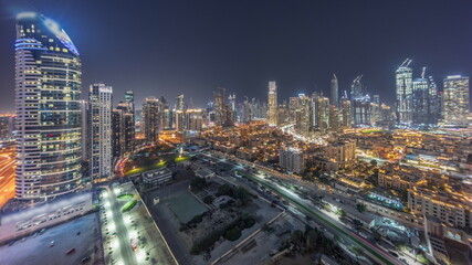 Naklejka na ściany i meble Dubai's business bay towers aerial night timelapse. Rooftop view of some skyscrapers