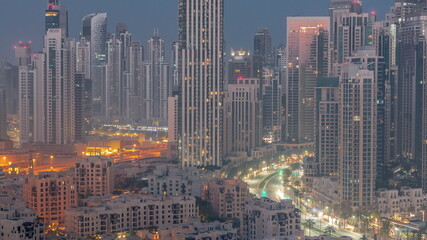 Futuristic aerial cityscape night to day timelapse with illuminated architecture of Dubai downtown, United Arab Emirates.