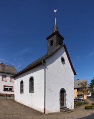 Fototapeta na wymiar Small baroque chapel with ridge turret and weathercock in the village of Sassen, Eifel region in Germany