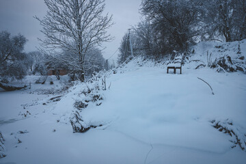 snow covered chair on river bank in December wintertime