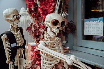 Halloween decoration near cafe or restaurant, modern skeletons sitting, talking, using mobile...