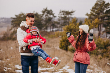 Young family together walking in forest at winter time