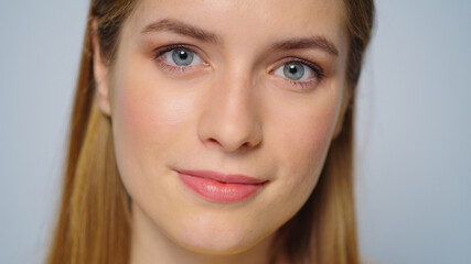 Naklejka premium Closeup pretty girl face smiling at camera on grey background.