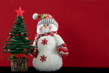 snowman and decorated Christmas tree isolated on red background