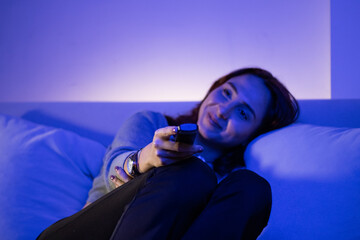 beautiful woman changing channels with remote, redhead young woman eating fruit while watching tv in her home