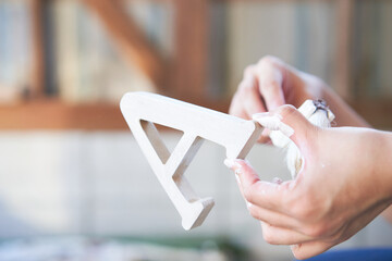 DIYでアルファベットを白いペンキで塗る女性の手元
